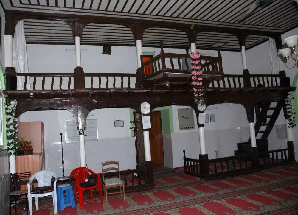 Sakarca Köyü Camii içinde ahşap direkler, mahfil, avize ve halıyla kaplı ibadet alanı