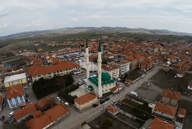 Orta ilçe merkezinin havadan görünümü; ortada iki minareli yeşil kubbeli bir cami ve çevresinde kırmızı çatılı yapılar