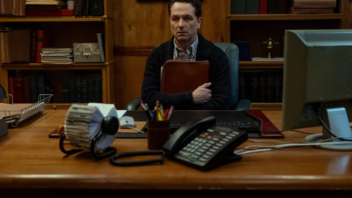 Widow's Bay dizisinde Belediye Başkanı Tom Loftis (Matthew Rhys) makam masasında arşiv dosyalarıyla